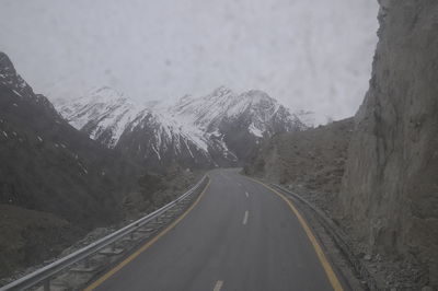 Road amidst snow covered mountains against sky