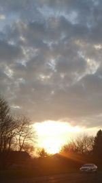 Scenic view of landscape against cloudy sky at sunset