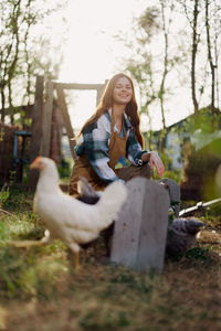 Portrait of young woman feeding chickens at farm