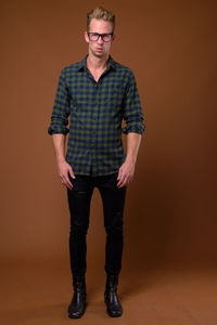 Portrait of young man standing against gray background