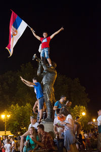 People with arms raised against clear sky at night