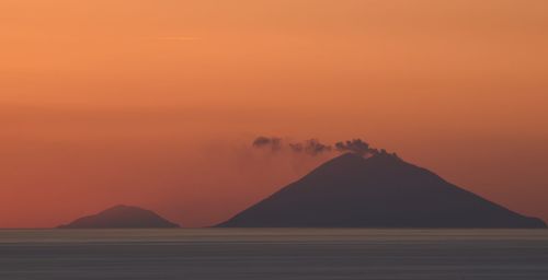 Scenic view of silhouette mountain against orange sky