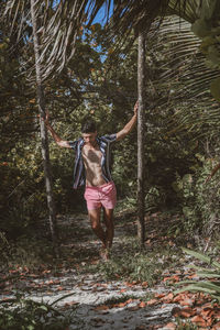 Full length of woman with arms raised in forest