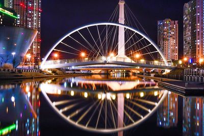 Illuminated bridge over river against sky at night