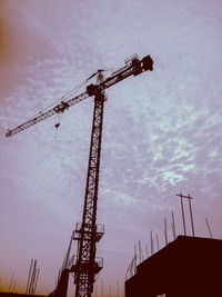 Low angle view of crane at construction site against sky