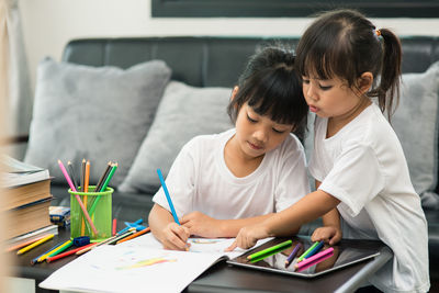 Cute siblings drawing on paper at home