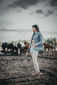 Full length of young woman with horse in background