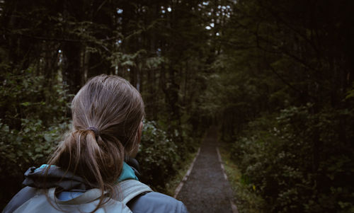 Rear view of woman amidst trees at forest