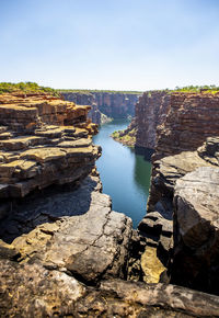 Rock formations by river against sky