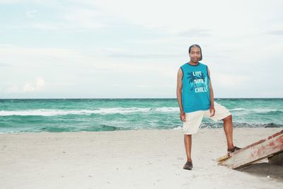 Full length portrait of man standing on beach against sky