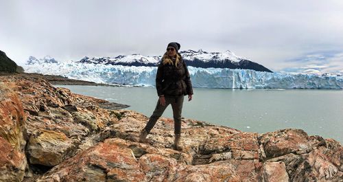 Mature woman wearing warm clothing while standing on rock by sea during winter