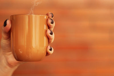 Cropped image of hand holding coffee cup 