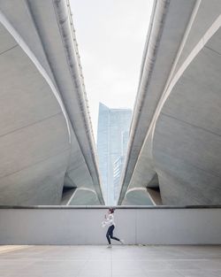 Side view of woman walking on bridge against buildings