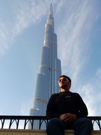 Low angle view of man sitting against sky