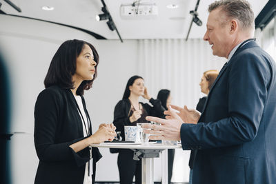 Businessman talking to businesswoman while gesturing at workplace