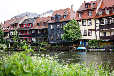 Houses by river and buildings against sky