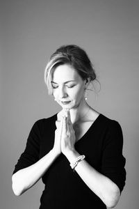 Young woman looking away while standing against wall