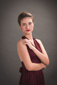 Portrait of beautiful smiling young woman against gray background