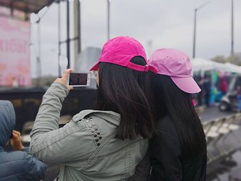 Side view of two women photographing while standing in city