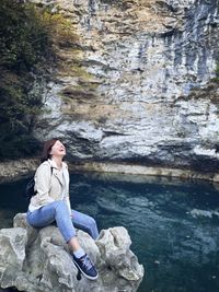 Woman sitting on rock by water