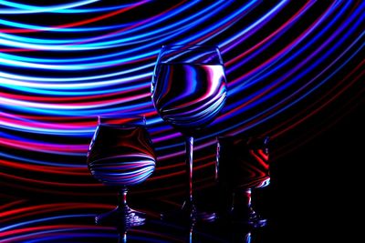 Close-up of drinks in wineglasses with light painting against black background