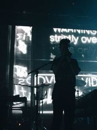 Rear view of silhouette man standing by window