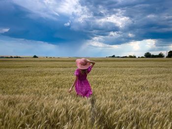 Rear view of woman standing on field against sky