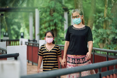The mother and daughter walking together in a public park during the covid-19 pandemic