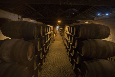Stacked barrels arranged in illuminated warehouse