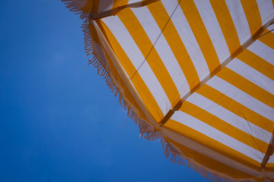 Low angle view of umbrella against clear blue sky