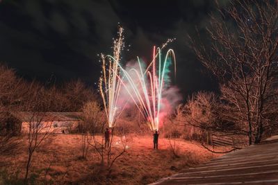 Men igniting fireworks on field at night