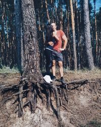 Full length of woman standing on tree trunk in forest