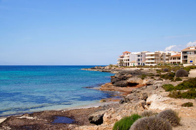 Scenic view of sea and empty beach with hotel against clear sky, mallorca 