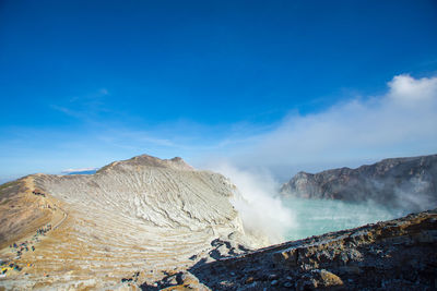 Panoramic view of volcanic mountain against blue sky