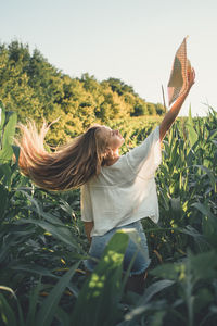 Woman with straw hat on corn  field against sky