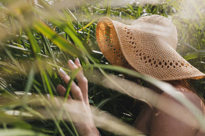 Woman wearing hat seen through plants