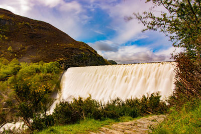 Scenic view of waterfall against sky