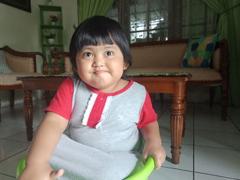 Portrait of cute girl standing on chair at home