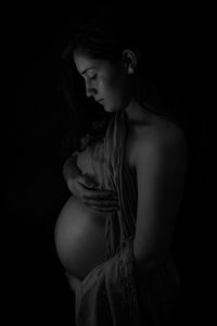 Midsection of woman standing against black background