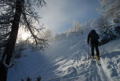 Rear view of man walking on snow covered landscape