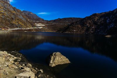 Scenic view of lake and mountains against clear blue sky