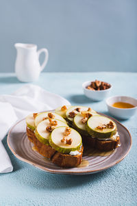 Appetizing sandwiches on rye bread with arugula, pear, honey and nuts on a plate vertical view