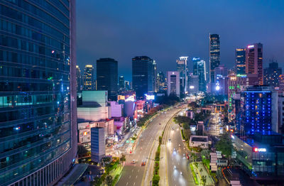 High angle view of illuminated street amidst buildings in city at night