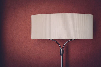 Close-up of lampshade against maroon wall