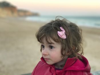 Close-up of cute girl wearing hair bow at beach during sunset