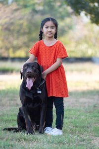 Portrait of girl with dog standing on field