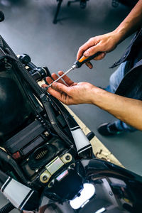 Low section of mature mechanic repairing motorcycle in garage