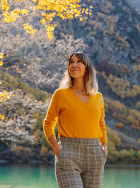 Young woman standing against lake