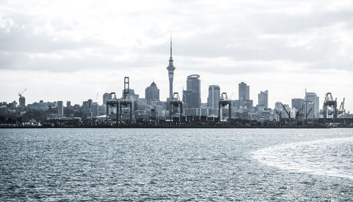 City at waterfront against cloudy sky