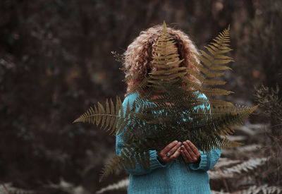 Rear view of woman standing against trees